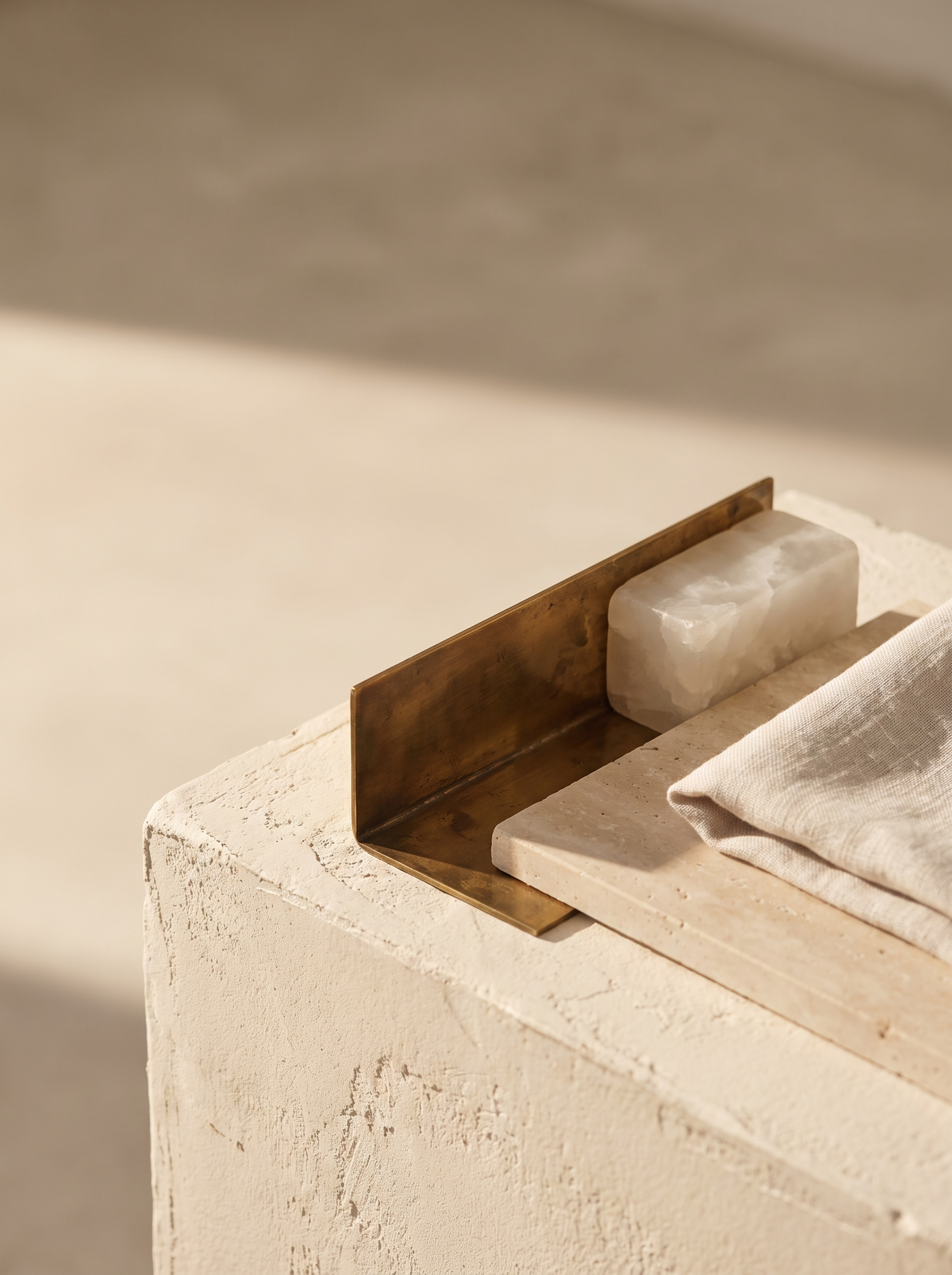 Brass, alabaster, travertine and linen arranged together under warm low light