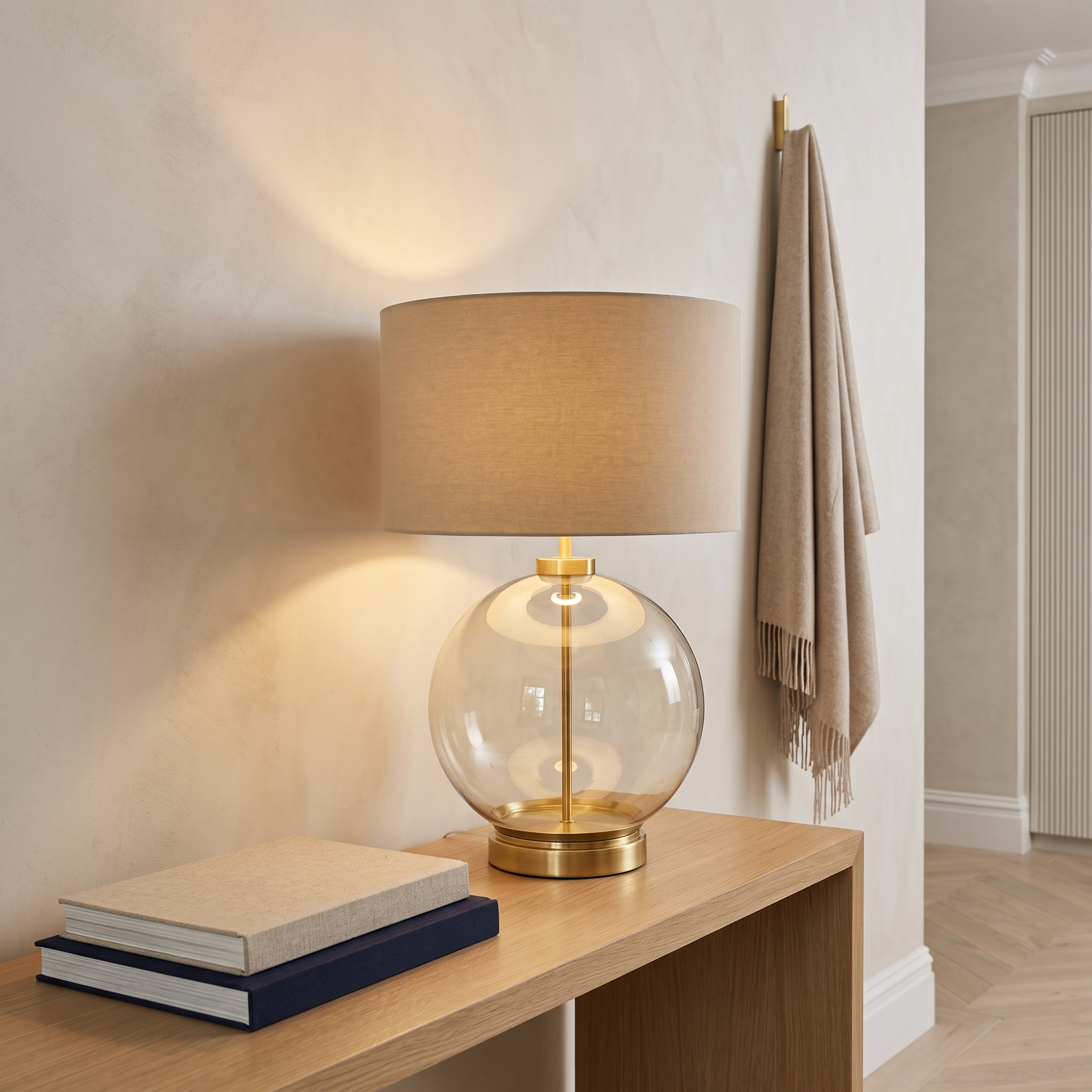 Atelierée Metro brass table lamp lit on a hallway console in a modern house