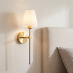 Atelierée Halston rechargeable brass wall light mounted beside a bed