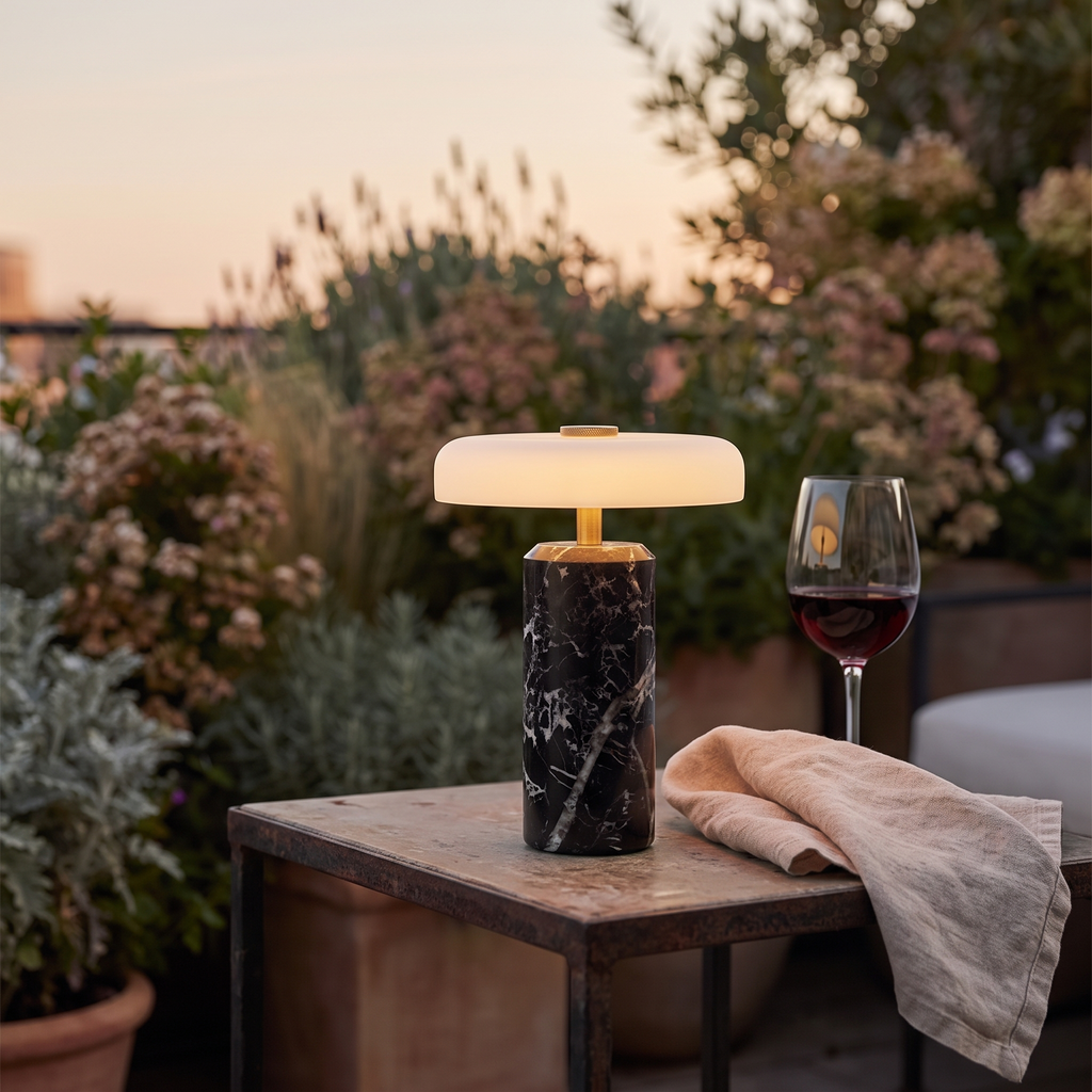 Atelierée Nero black marble rechargeable table lamp on an outdoor terrace table at dusk