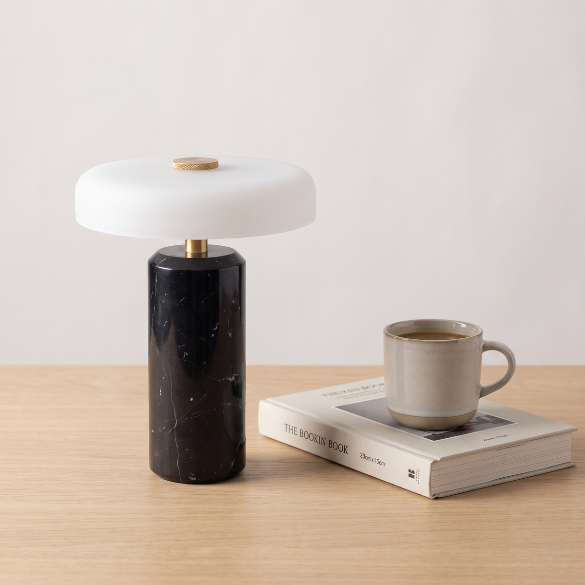 Atelierée Nero black marble table lamp shown beside a book and mug for scale