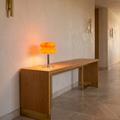 Italian designer glass table lamp lit on an oak console in a hallway
