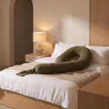 Adjustable full body pregnancy pillow curved across a made bed