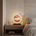 Quicksand rotating LED table lamp lit on an oak bedside table