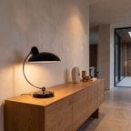 Bauhaus inspired curved metal table lamp on an oak sideboard