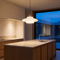 White glass pendant light above a kitchen island at blue hour
