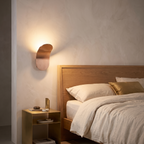 Minimalist LED wall lamp lit beside a bed