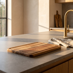 Three piece book shaped bamboo and wood chopping board set on a honed stone kitchen worktop