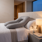 Full length body pillow curved along a made bed