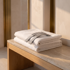 Set of elastic sheet gripper straps laid on a folded stack of white bedding on an oak bench
