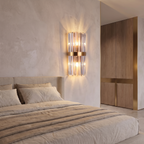 Stainless steel crystal wall sconce mounted on a plaster wall beside the head of a bed