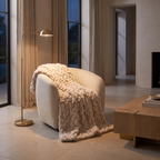 Ruched faux fur throw blanket draped over a boucle armchair