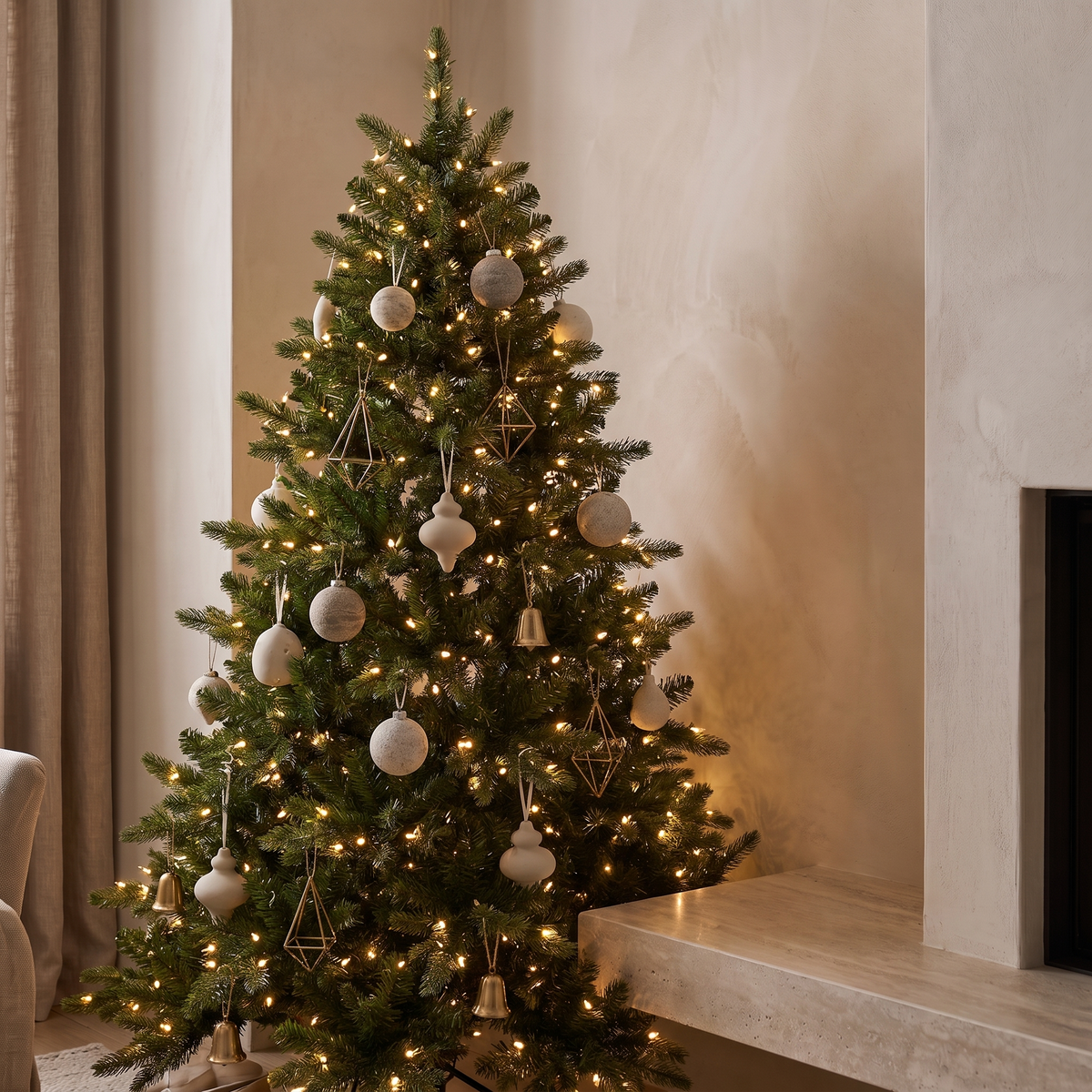Pre lit artificial Christmas tree beside a honed stone fireplace