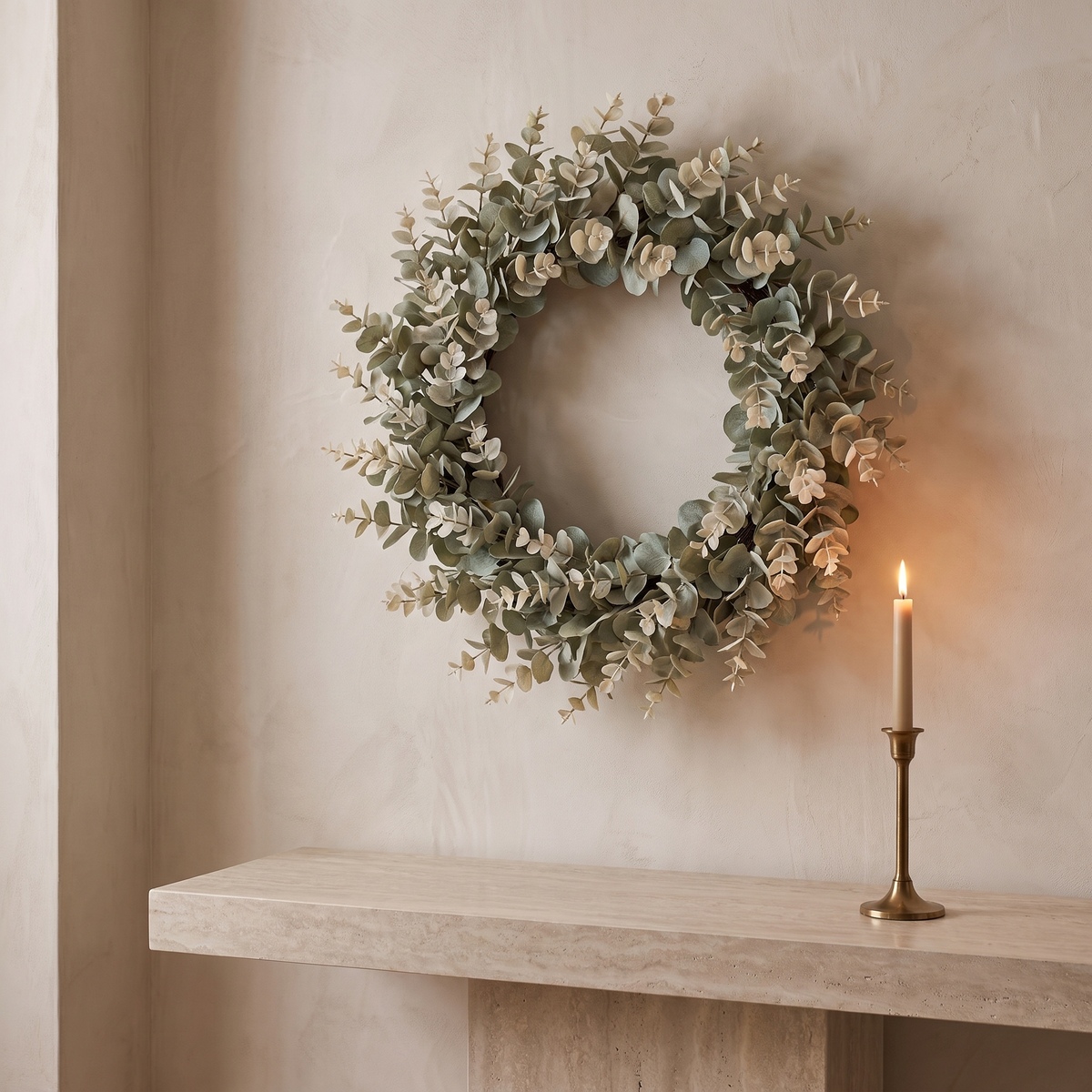 Eucalyptus wreath hung above a stone console with a brass candlestick