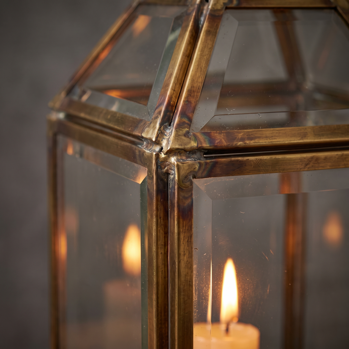 Close detail of the brass frame and glass panel of a candle lantern