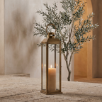 Brass and glass candle lantern lit on a sheltered terrace at dusk