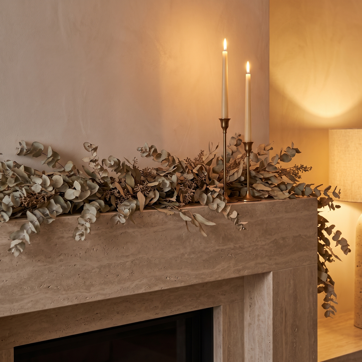 Eucalyptus garland draped along a stone mantelpiece with brass candlesticks