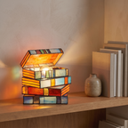 Stained glass book lamp lit on a living room bookshelf