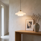 White glass pendant light in a hallway above a console table