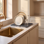 Countertop drain pad beside a kitchen sink with dishes draining