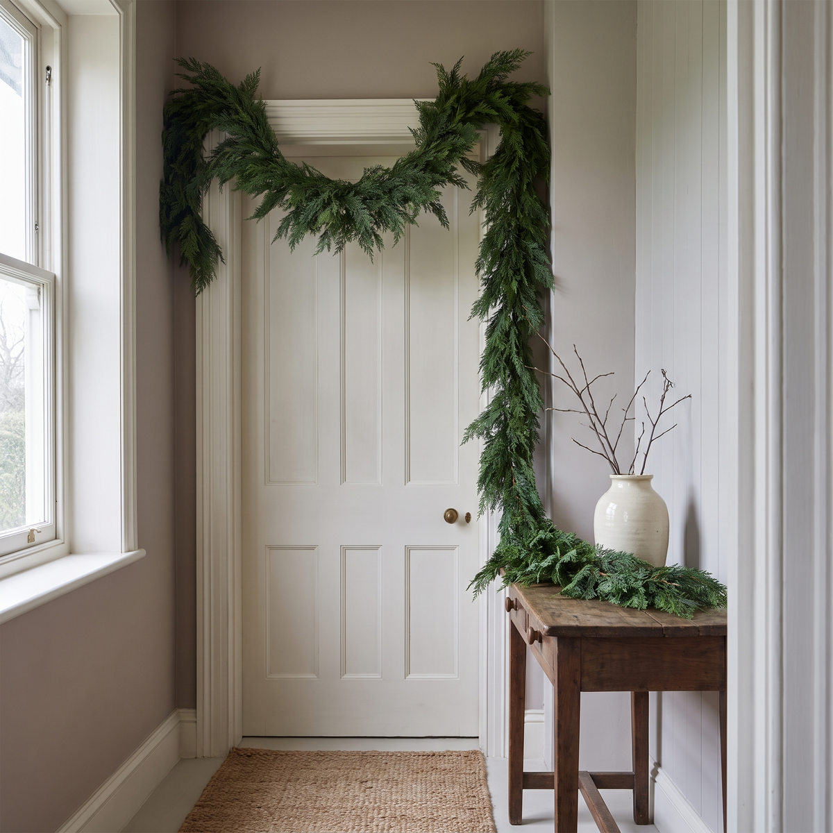 Thornwood cedar garland swagged above a panelled front door in a bright hallway