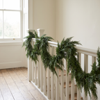 Thornwood cedar garland draped along a white painted staircase bannister