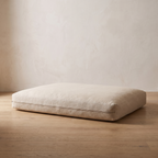 Atelieree Sorrel linen dog mattress on an oak floor against a pale plastered wall