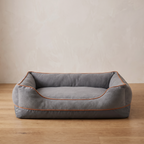 Atelieree Halston bolster dog bed on an oak floor against a pale plastered wall