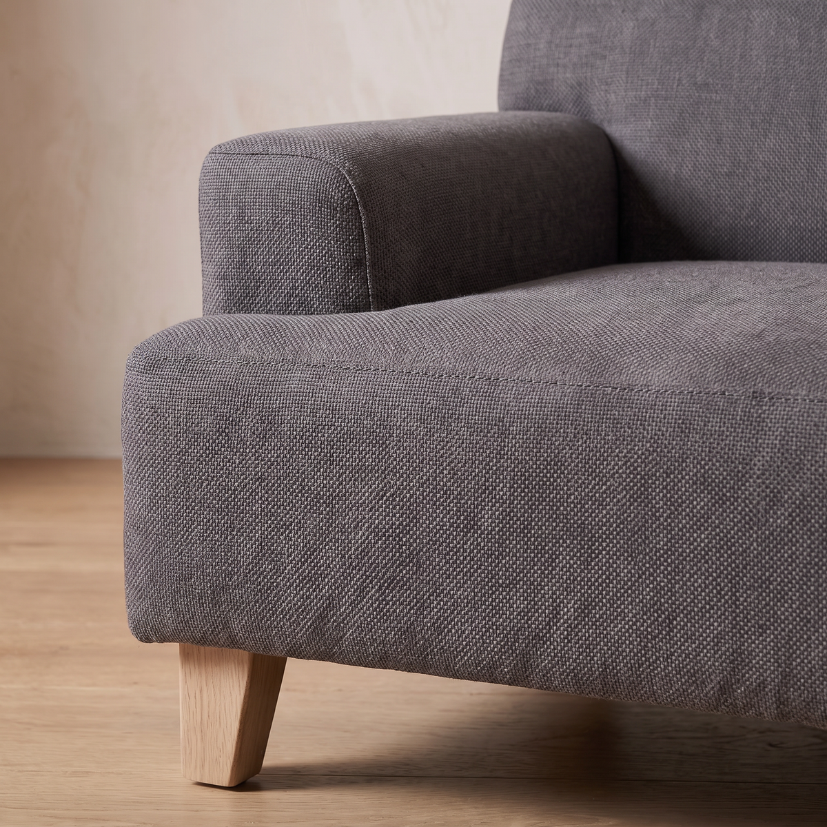 Close detail of the woven cotton armrest seam and pale oak leg on the Atelieree Linnea pet sofa