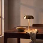 The gold mushroom lamp lit on the dining table in the evening with no cable visible