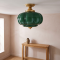 The green glass ceiling light fitted in a pale plaster hallway above an oak console table, switched off