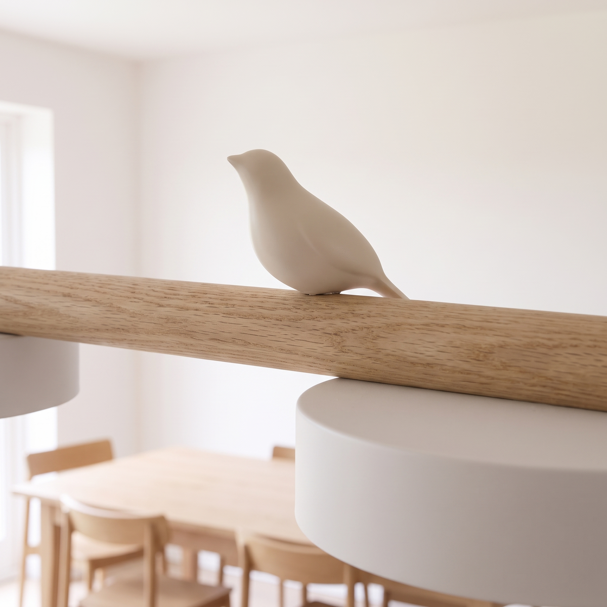 Close detail of a moulded resin bird perched on the wooden bar above a disc shade