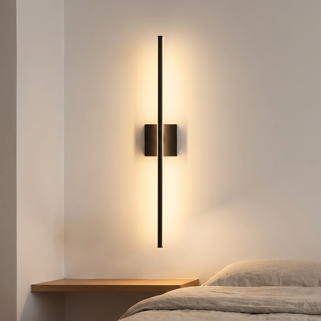 Filo slim black wall light mounted vertically above a bedside shelf