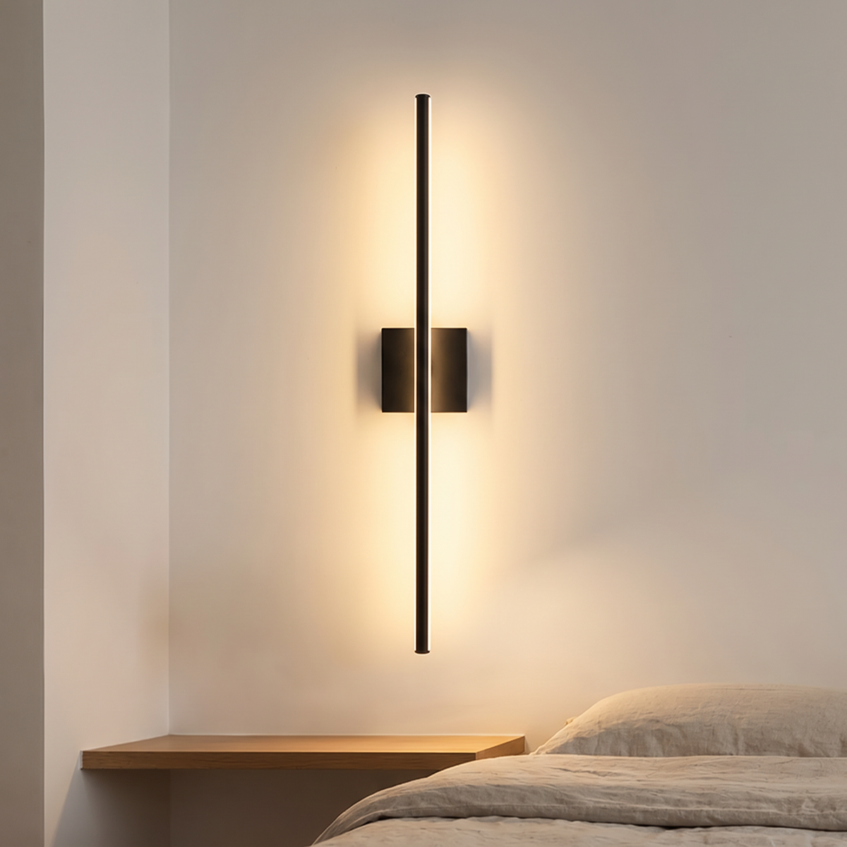 Filo slim black wall light mounted vertically above a bedside shelf