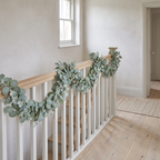 Eucalyptus garland draped along a pale oak staircase bannister